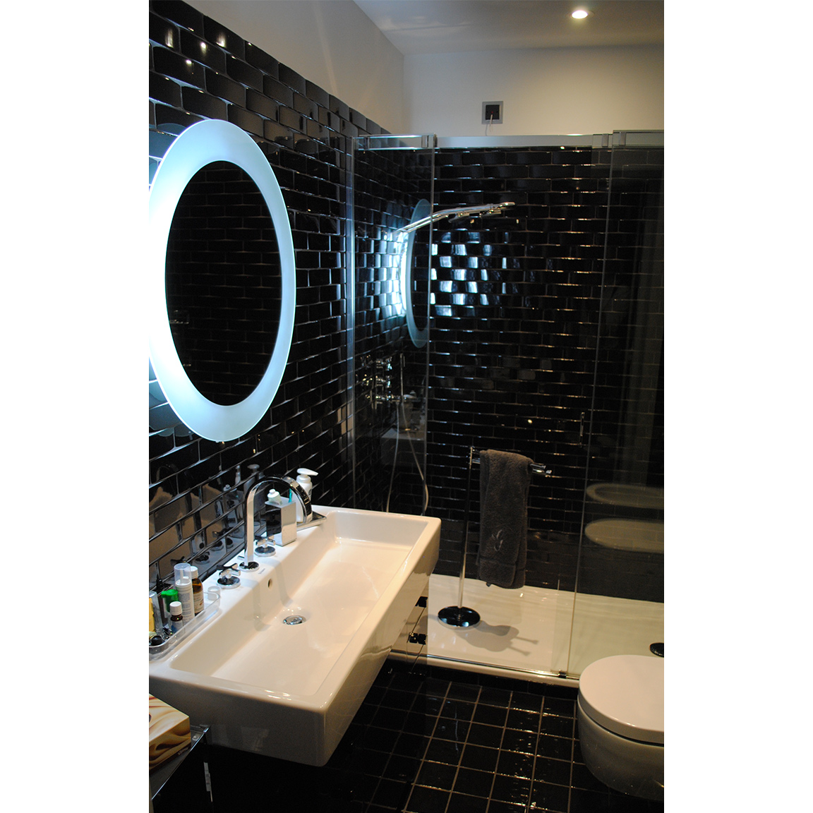 round neon mirror frame inside black bathroom