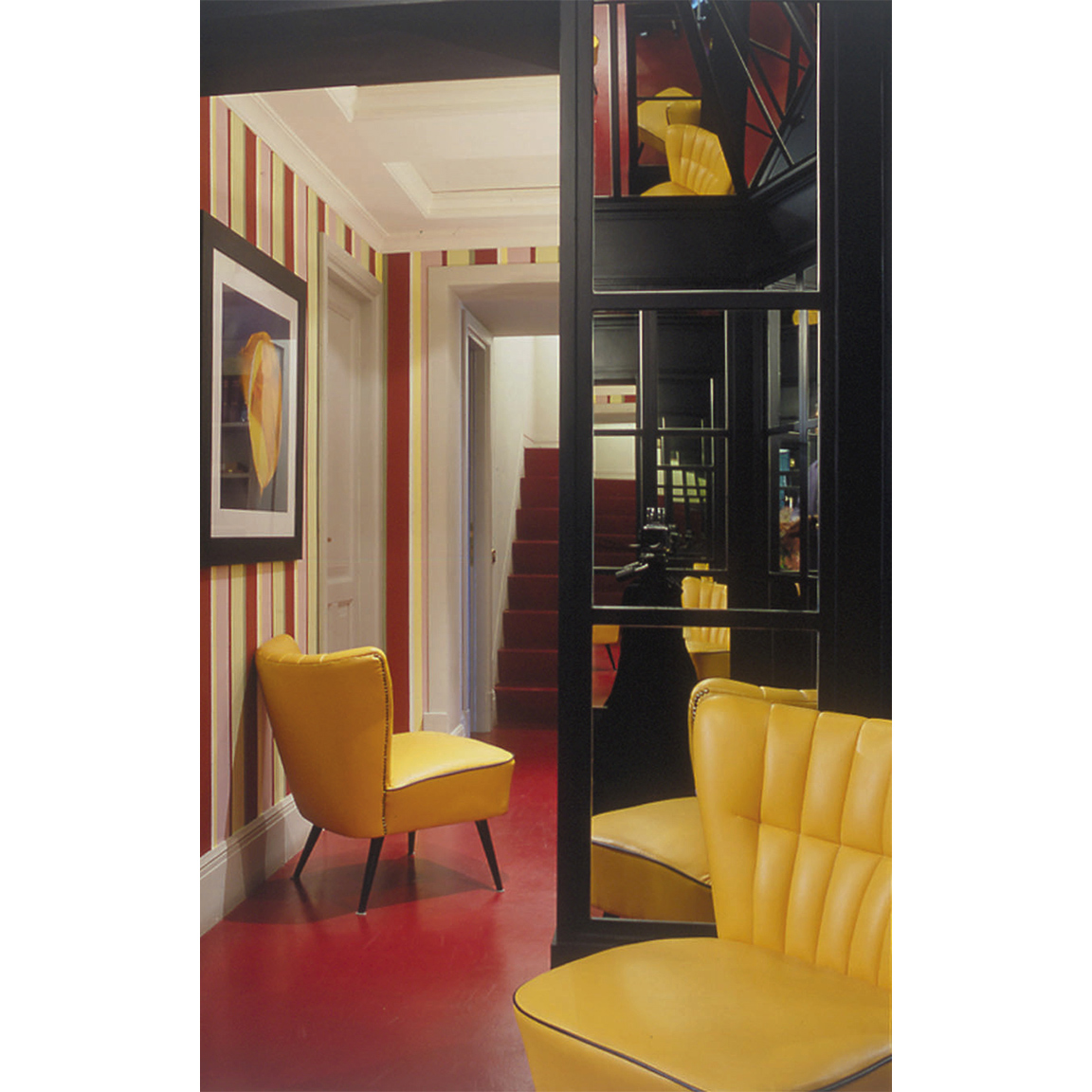 yellow armchairs in a hallway with red floor and striped colorful wallpaper