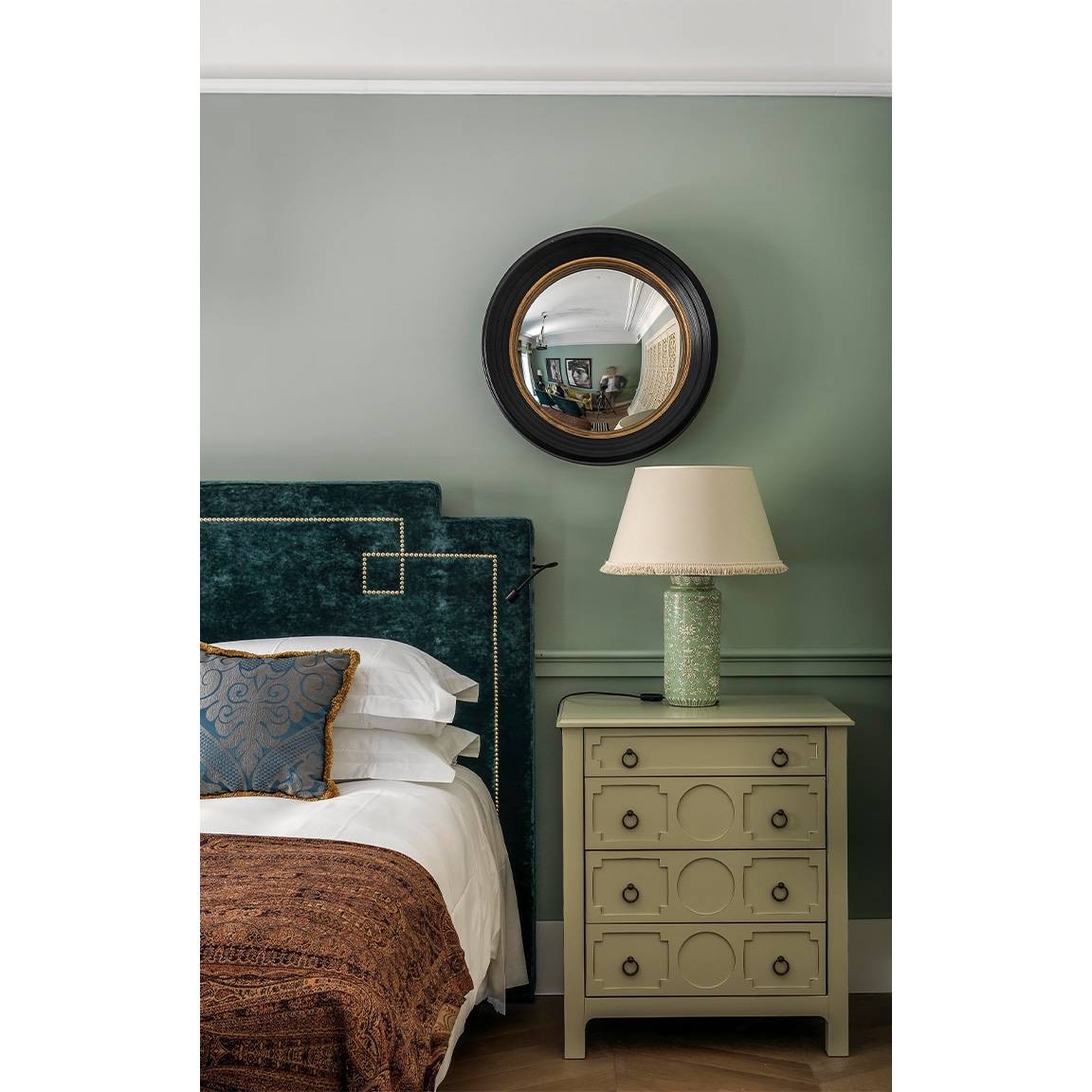 rounded mirror over a bed with bedside table